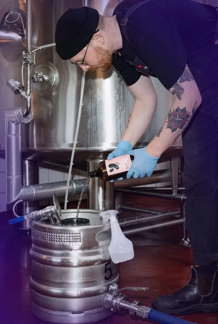 A brewer pouring Yops® into a keg
