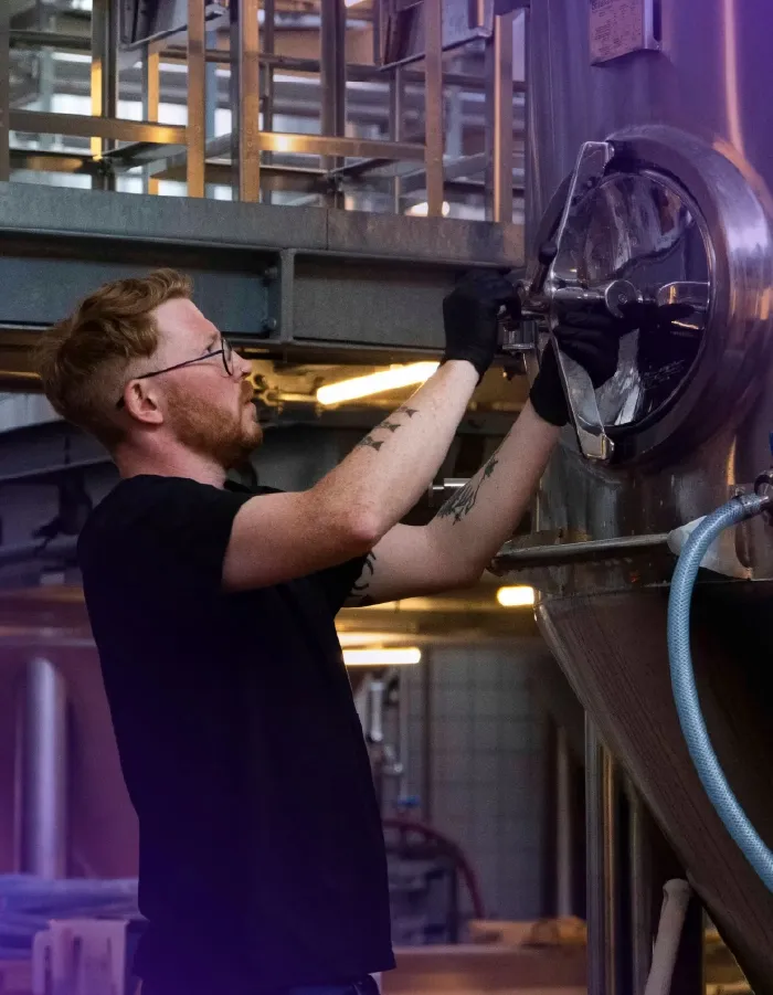 A brewer working at a fermentation tank